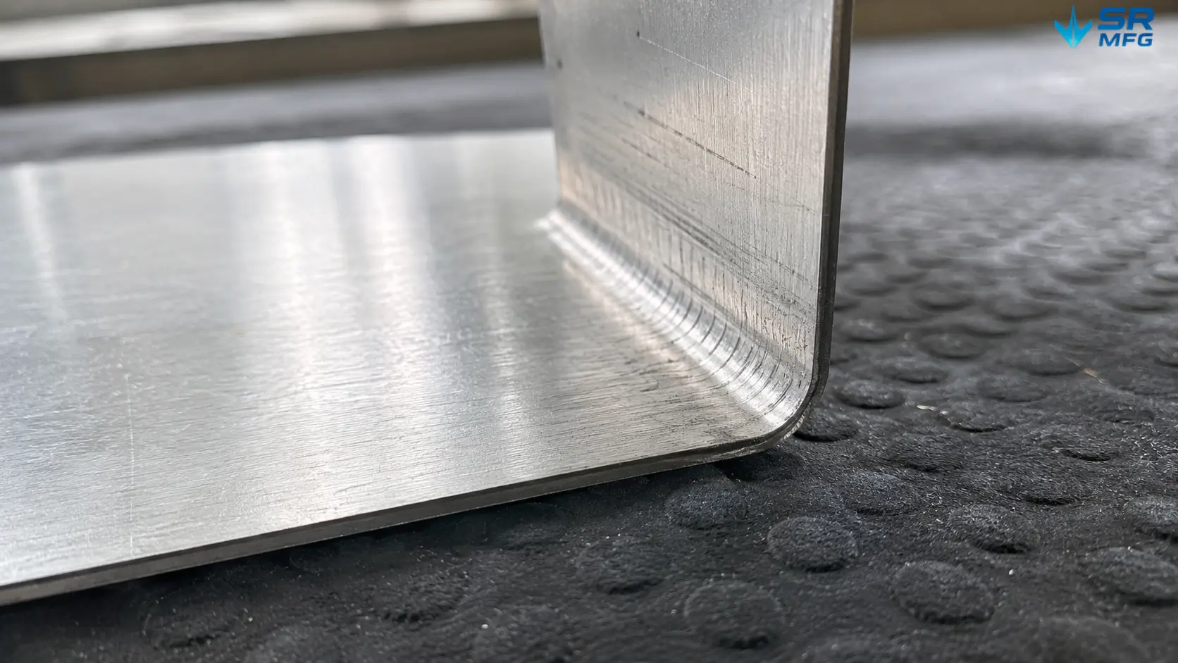 Macro view of tool marks and pressure impressions left on 1.2mm polished stainless steel sheet after press brake bending