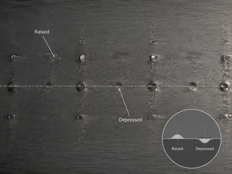 Macro photograph showing periodic raised and depressed roll mark defects on hot-rolled steel strip surface